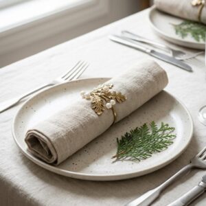 Gold leaf napkin ring with pearl-style accents on a neutral linen napkin