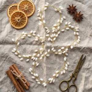 White elongated beads on gold-tone wire arranged as a decorative Christmas garland