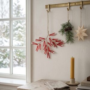Red and white branching Christmas sprig hanging on a wall beside festive decorations