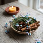Blue and lavender decorative beads arranged on gold-tone wire among evergreen branches and cinnamon sticks